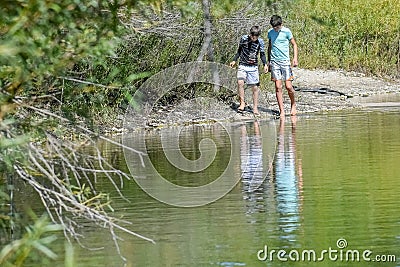 Two Boys Walking Along Shoreline of Beach Stock Photo