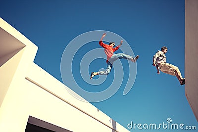 Two brave men jumping over the roof Stock Photo