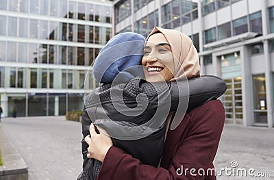 Two British Muslim Women Friends Meeting Outside Office Stock Photo