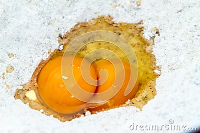 Two broken fresh eggs in flour Stock Photo