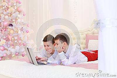 Two of brother`s children play computer games and lie on bed in Stock Photo