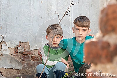Two brothers are orphans, hiding in an abandoned house, frightened by the disaster and hostilities. Submission photo Stock Photo