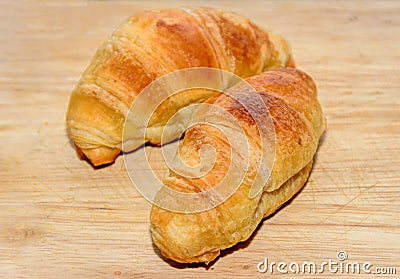 Two brown baked croissants, wooden plate, close up Stock Photo