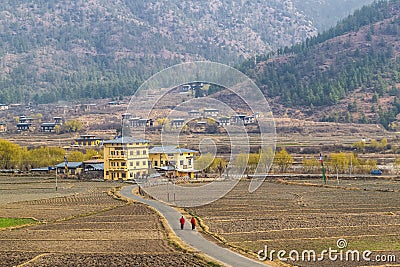 Two Buddhist monks in traditional red clothes walk along the road to the village. Mountains of the Himalayas on the horizon. Stock Photo