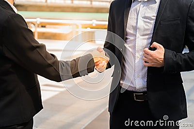 Two business man shaking hands for demonstrating their agreement to sign agreement or contract between their firms / com Stock Photo