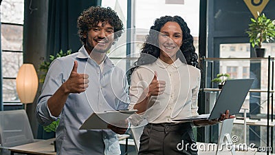 Two business partners colleagues Arabian businessman discuss with Hispanic businesswoman documents laptop project office Stock Photo
