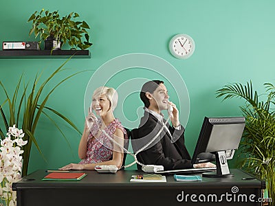 Two business people talking on entangled phones in office Stock Photo