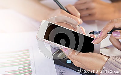 Two business woman hand writing and using mobile phone for their work analyzing on financial project with business graph Stock Photo