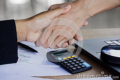 Two business woman handshake after working together and agree on their project at office with some financial paper graph Stock Photo