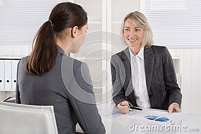 Two business woman sitting at desk: customer and adviser talking Stock Photo