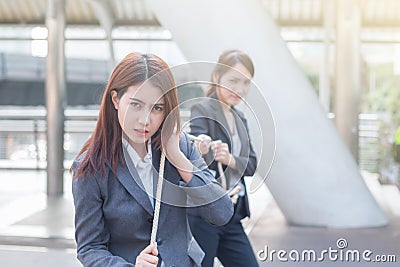Two business women pulling a rope competing with commitment to winer Stock Photo