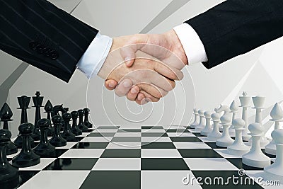 Two businessman hands shake hands with on the chess background Stock Photo
