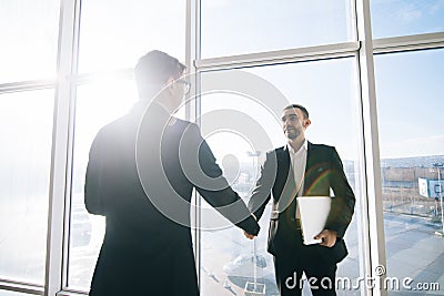 Two businessmen greeting in sunny office room Stock Photo