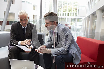 Two Businessmen Meeting In Lobby Area Of Modern Office Stock Photo