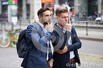 Two businessmen standing in street and looking at something Stock Photo