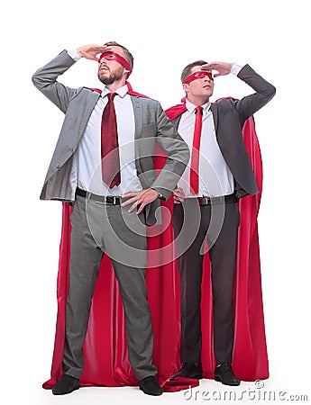 Two businessmen in superhero raincoats looking in different directions. Stock Photo