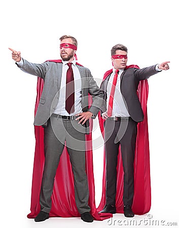 Two businessmen in superhero raincoats pointing in different directions. Stock Photo
