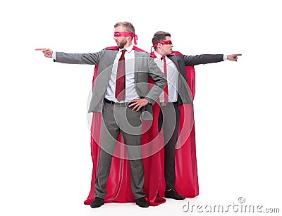 Two businessmen in superhero raincoats pointing in different directions. Stock Photo