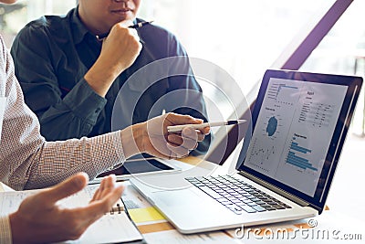 Two businessmen are together analyzing the financial data graph and pointing to the laptop computer screen Stock Photo