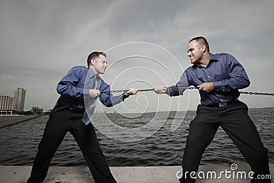 Two businessmen tugging on a chain Stock Photo