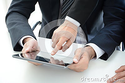 Two businessmen using tablet computer with one hand touching screen Stock Photo