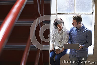 Two Businesspeople Having Informal Meeting On Office Stairs Stock Photo