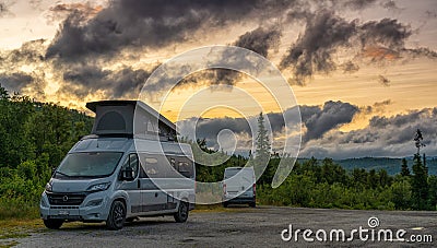 Two camper vans parked in the wilderness of northern Sweden under a colorful sunset sky Editorial Stock Photo