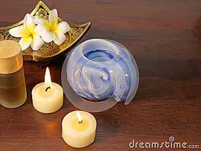 Two candles, a gold pattern dish, and aromatherapy bottle Stock Photo