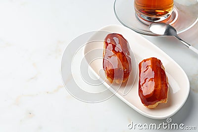 Two caramel eclairs on a white plate Stock Photo