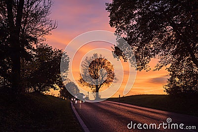 Two cars on rural road with automobile headlight on at sunset Stock Photo