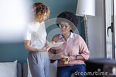 Two casual young business women working with the digital tablet in the new office Stock Photo