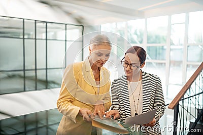 Two Caucasian concentrated female coworkers standing in the hall Stock Photo