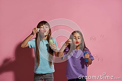 Two caucasian little girlfriends blow soap bubbles Stock Photo