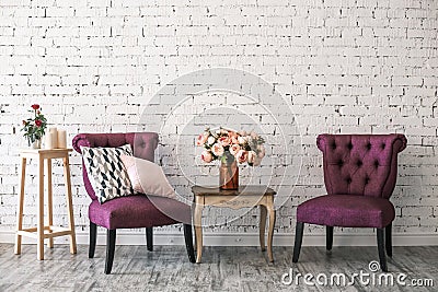 Two chairs and a table with bouquet of flowers in a vase near white brick wall vintage style Stock Photo