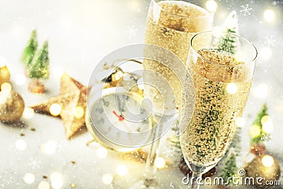 Two champagne glasses with moving bubbles and christmas decoration over gray golden bokeh background. Happy New Year Celebration. Stock Photo