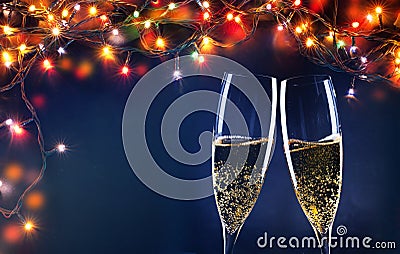 two champagne glasses ready to bring in the New Year - holiday lights and fireworks in the background Stock Photo