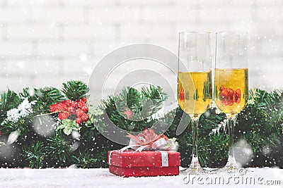 Two champagne glasses setting next to a red gift box on snowy ta Stock Photo