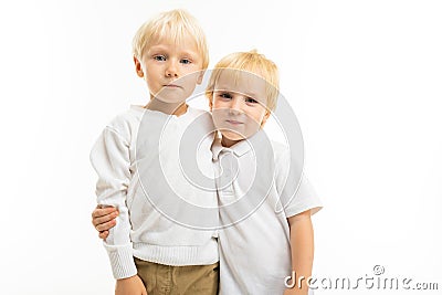 Two charming blond brother children in an embrace on a white background Stock Photo