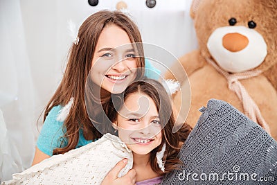 Two cheerful charming sisters playing with pillows Stock Photo