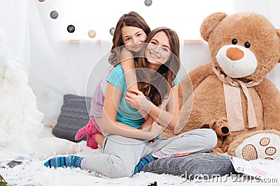 Two cheerful charming sisters sitting in children room Stock Photo