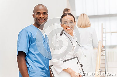 Two cheerful doctors looking over shoulder and smiling while the Stock Photo