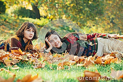 Two cheerful girls . Girl with her best friend. Two women in a park. Two beautiful teenage girls lying in the autumn Stock Photo