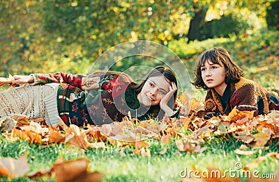 Two cheerful girls . Girl with her best friend. Two women in a park. Two beautiful teenage girls lying in the autumn Stock Photo