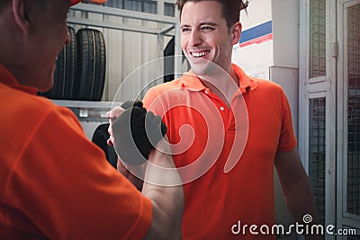 Two cheerful and happy worker men giving touching hands and hi five during working in garage automobile service center. car Stock Photo