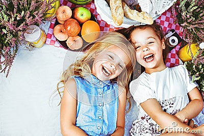 Two cheerful kids lying on a picnic blanket among refreshments Stock Photo