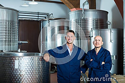 Two cheerful men in uniforms standing in winery fermentation compartment Stock Photo