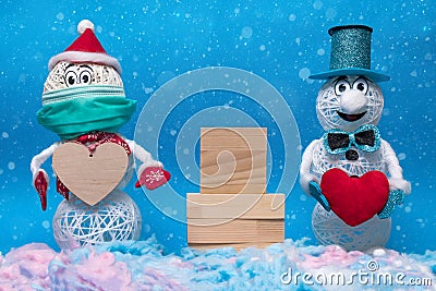 Two cheerful snowmen stand in the snow, between them there is a wooden pedestal for the inscription, valentine's day Stock Photo