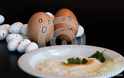 two chicken eggs scared, on the table is fried egg in the white plate Stock Photo