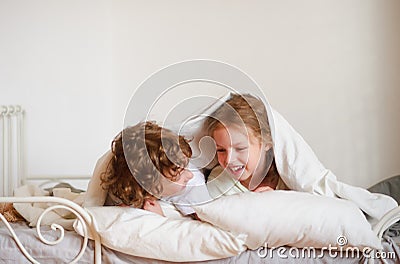 Two children, boy and girl, squirmy lying on the bed in the bedroom. Stock Photo