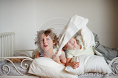 Two children, brother and sister, indulge on the bed in the bedroom. Stock Photo